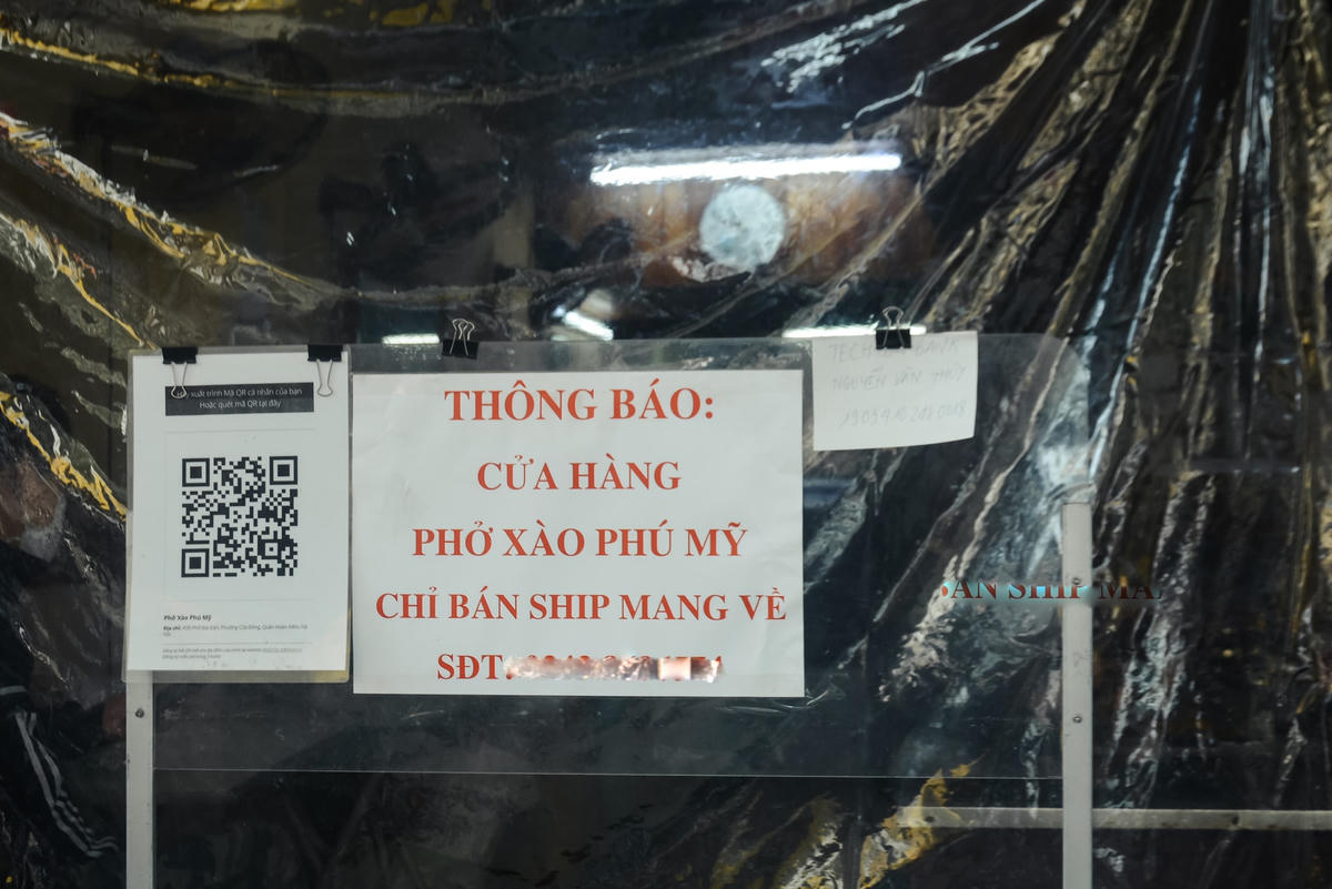 Cửa hàng phở xào ở phố Bát Đàn, phường Cửa Đông, quận Hoàn Kiếm đã căng tấm chắn để khách không vào, yêu cầu khách đến mua hàng mang về phải quét mã QR.