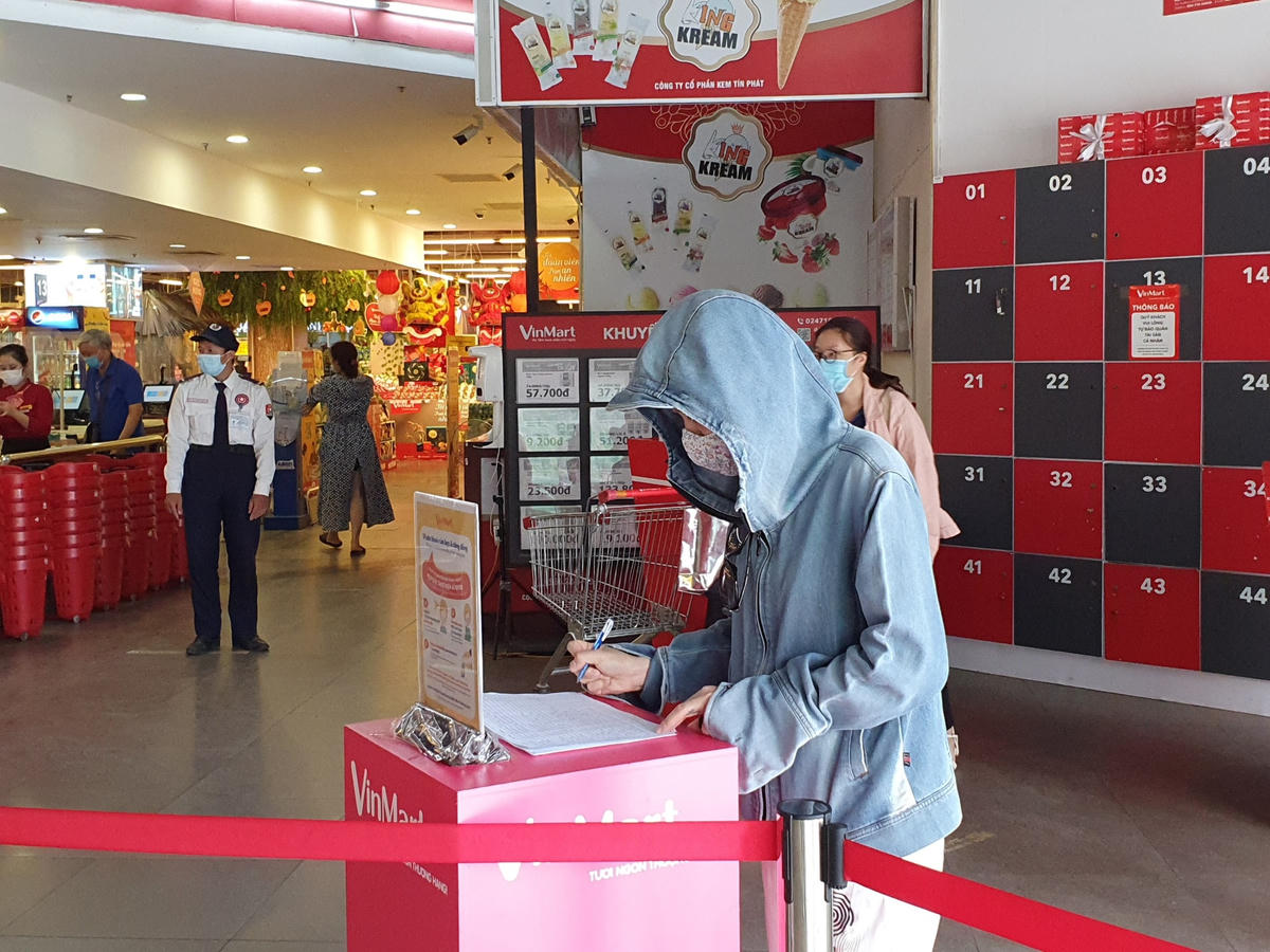 Người dân thực hiên việc khai báo y tế thông qua điền tờ khai truyền thống tại Vinmart Thăng Long.