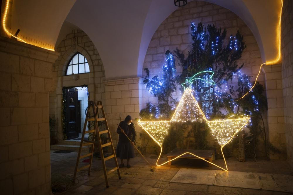 Một nữ tu lau sàn sau khi trang trí lối vào nhà thờ bằng đèn Giáng sinh ở Thành phố Cổ của Jerusalem. Ảnh: AP.