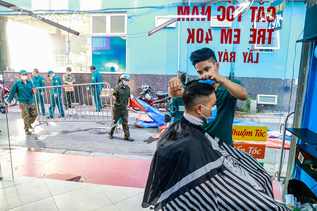 Anh Hải thợ cắt tóc quê ở Ninh Bình đã mở cửa hàng từ 6h00, lúc anh đang cắt tóc cho vị khách đầu tiên cũng là lúc lực lượng chức năng gỡ bỏ chốt cứng trước cửa hàng của mình.