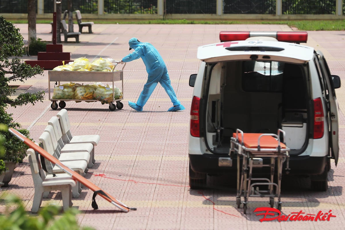 Dưới trời nắng 38 độ, cán bộ, nhân viên, chiến sỹ trong khu cách ly vẫn mặc đủ đồ bảo hộ thực hiện nhiệm vụ chia cơm tới từng phòng cho công dân. Ảnh: Quang Vinh. 