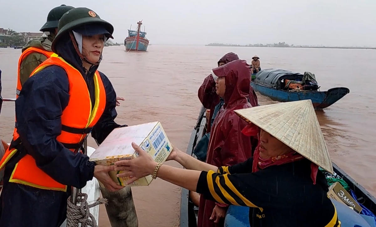 Chị Trần Thị Tuyết Lan, Phó Chủ tịch Ủy ban MTTQ Việt Nam thị xã Ba Đồn trao hỗ trợ người dân ở vùng cồn bãi sông Gianh trong đỉnh lũ.