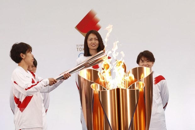 Vận động viên bóng đá Nhật Bản Azusa Iwashimizu (trái) thắp sáng ngọn đuốc Olympic tại lễ rước đuốc Olympic Tokyo 2020, ở Naraha, tỉnh Fukushima, Nhật Bản, ngày 25/3/2021. Ảnh: AFP/TTXVN.  