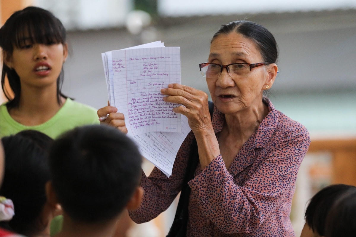 Sau phần điểm danh, bà giáo về hưu nhận xét từng bài kiểm tra của học trò. "Từng bài tôi đều có lời phê kỹ càng và nhận xét cụ thể. Em nào làm bài tốt, thể hiện sự tiến bộ tôi đều đề nghị cả lớp vỗ tay động viên", bà Ba nói.  