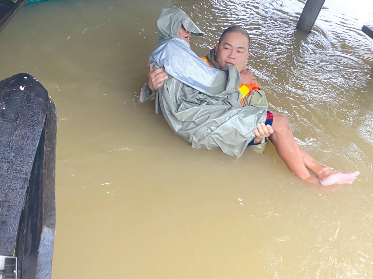 Nhà báo Lê Hữu Chính cứu người trong lũ. Ảnh: Xuân Thi.