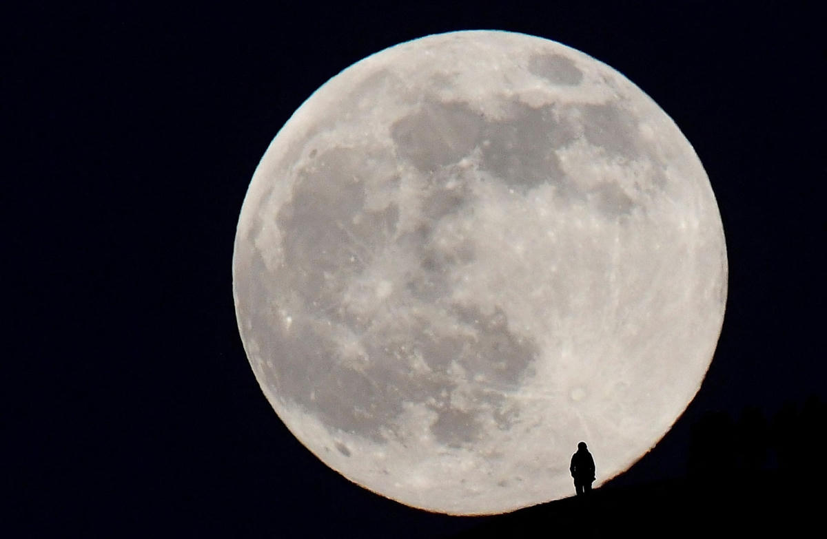 Khoảnh khắc một người đứng trên sườn đồi Glastonbury Tor ngắm Trăng tròn. Ảnh: Toby Melville / Reuters.