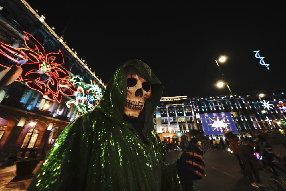 Một người hóa trang thành La Santa Muerte (Đức Mẹ Thánh Tử Thần) chụp ảnh tại quảng trường chính Zócalo trong thành phố Mexico, khi ánh đèn Giáng sinh tỏa sáng. Ảnh: AP.