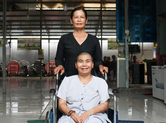 Chị Nguyễn Thị Bảy (ngồi xe lăn), 40 tuổi, bị bệnh tâm thần, là người ở huyện Nhơn Trạch sống lang thang ngoài đường từ nhỏ đến lớn, ai cho gì ăn nấy. Chị Bảy có duy nhất một người cha nhưng ông cũng đang chăm sóc một người mẹ già. Ba năm trước, bà Hồng nhận nuôi nhưng mỗi khi lên cơn chị lại trốn đi. Đợt dịch Covid-19 năm nay bà Hồng sửa lại hàng rào chắc chắn, đón chị về chăm sóc vì sợ chị đi ngoài đường nhiều dễ nhiễm bệnh. Ảnh: Vnexpress.