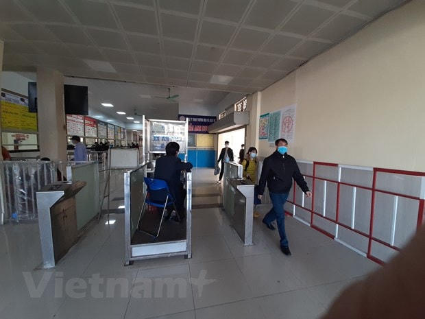 Nhân viên bến xe nhắc nhở hành khách phải đeo khẩu trang mới được vào trong bến. (Ảnh: Việt Hùng/Vietnam+).