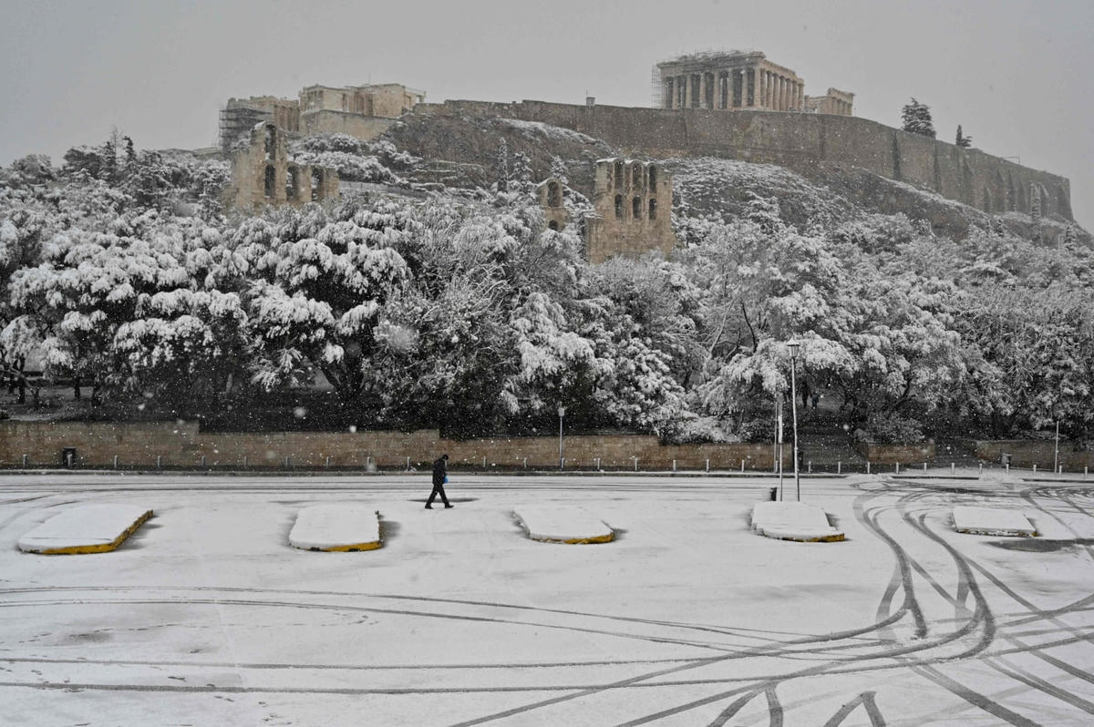 Một người đàn ông sải bước trước “thành phòng thủ" Acropolis tại trung tâm Athens khi tuyết trắng bao trùm thành phố. Ảnh: Louisa Gouliamaki / AFP / Getty Images.