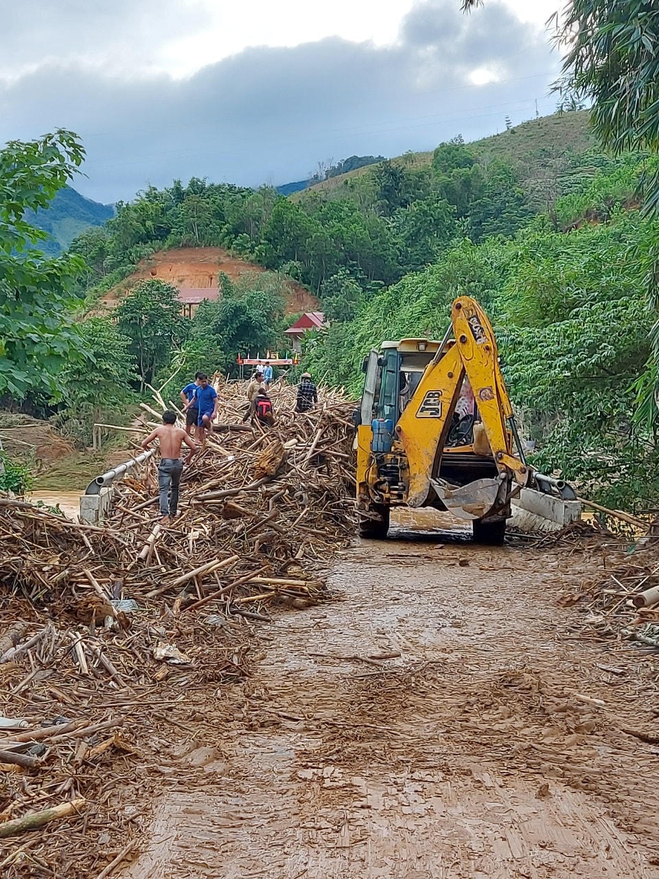 Xe cơ giới dọn dẹp cây cối, đất đá do mưa lũ đem đến.