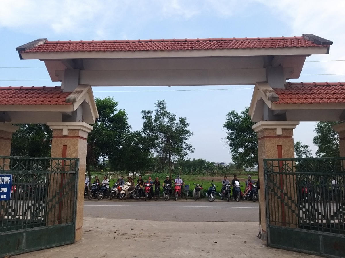 Ở phía ngoài cổng trường, phụ huynh đến đón con em, trong lúc chờ đợi cũng phải chấp hành quy định người xe đứng xếp hàng dọc theo lề đường phía đối diện cổng trường.