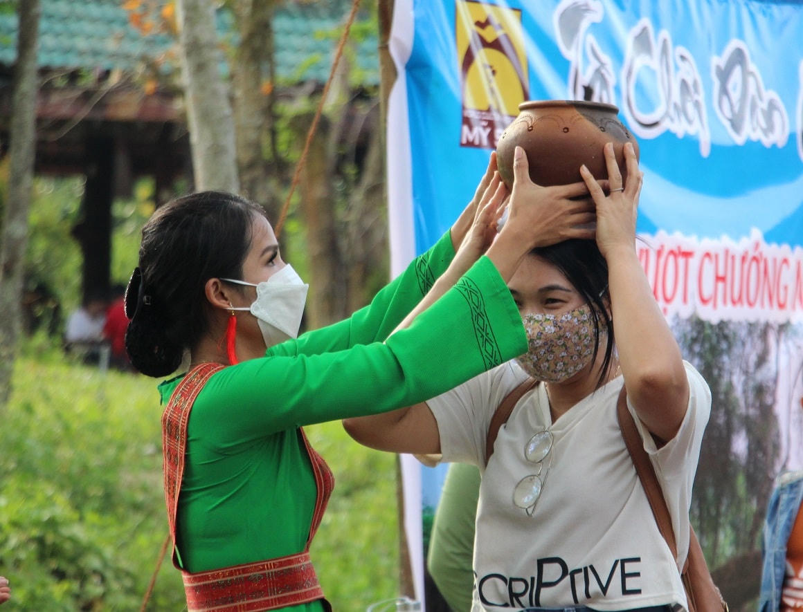 Một du khách tham gia vào trò chơi đội nước của người Chăm Pa.