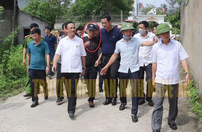 Cao Trọng Phú (khoanh đỏ) được dẫn giải ra khỏi nhà tay không bị còng khiến nhiều người thắc mắc (Ảnh THANNA)