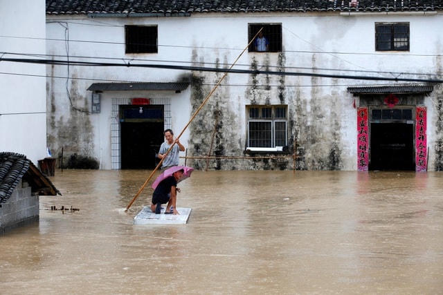 Người dân Trung Quốc di chuyển trên bè tự chế do lũ lụt ở tỉnh An Huy hôm 6/7 (Ảnh: Reuters).