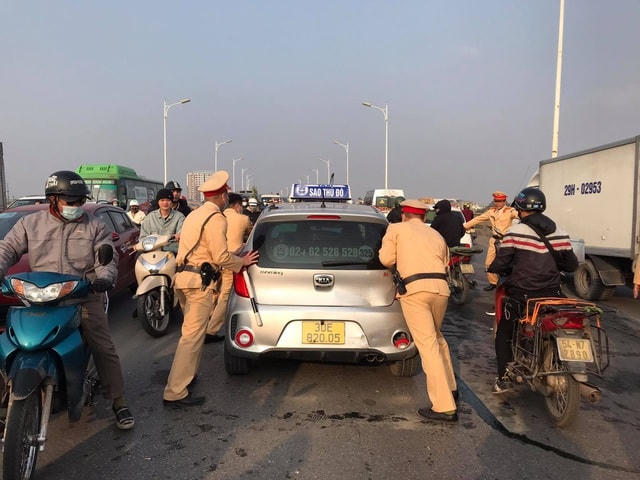 Lực lượng chức năng đẩy chiếc taxi rời khỏi hiện trường sau khi tiến hành khám nghiệm.