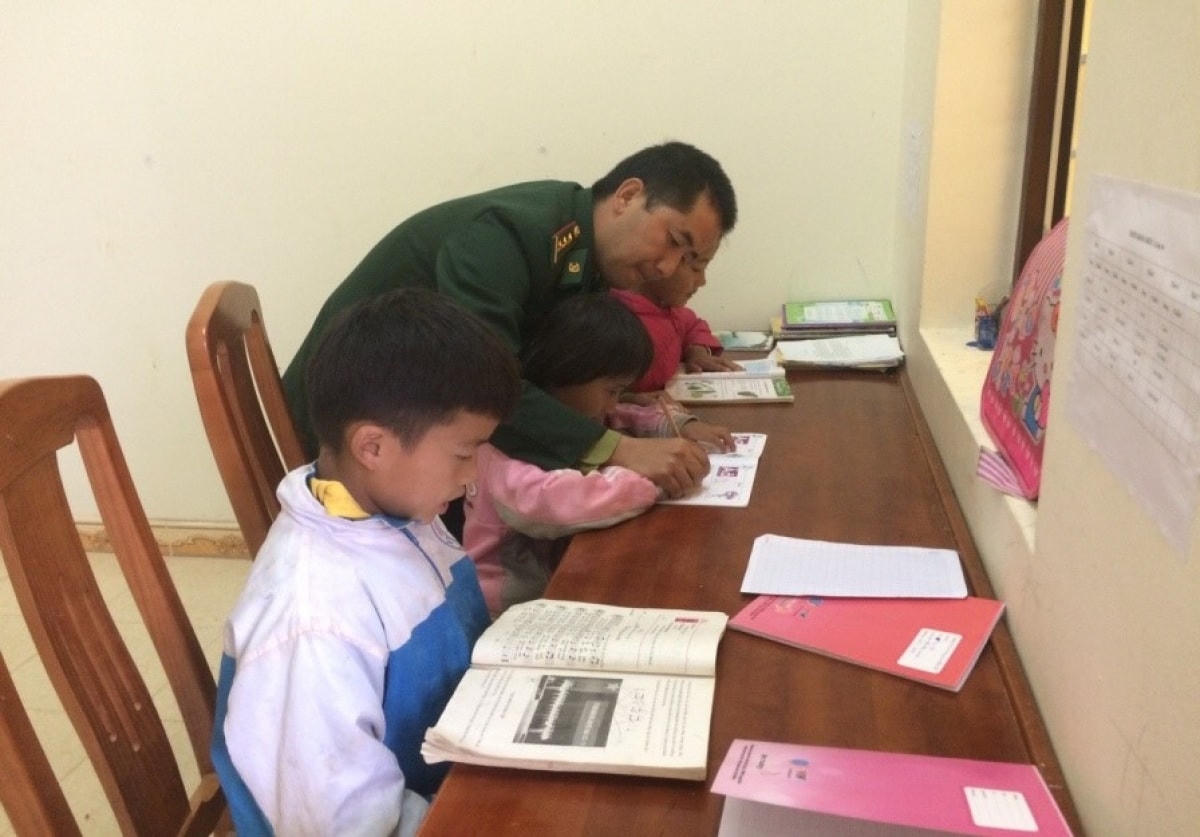 Đại úy Vừ Mí Chứ hướng dẫn các con học bài. Ảnh: NVCC.  