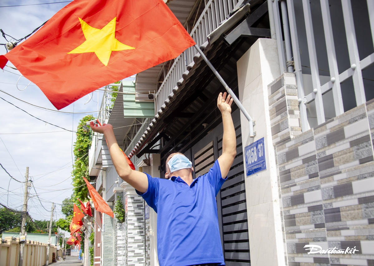 Người dân phấn khởi hưởng ứng việc treo cờ Tổ quốc quyết tâm chiến thắng đại dịch.