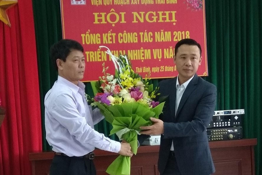 Ông Hoàng Văn Thành, Giám đốc Sở Xây dựng Thái Bình thời điểm năm 2018 (áo trắng) tặng hoa, chúc mừng ông Phùng Văn Chiến trong ngày được trao quyết định bổ nhiệm làm Viện trưởng Viện quy hoạch xây dựng, thuộc Sở.