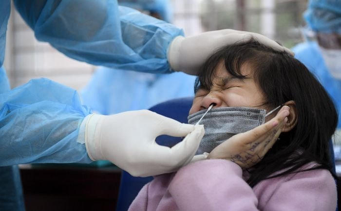 Một học sinh tại lớp 3E, trường Tiểu học Xuân Phương lấy mẫu dịch mũi để xét nghiệm SARS-CoV-2. Ảnh: Việt Hùng.