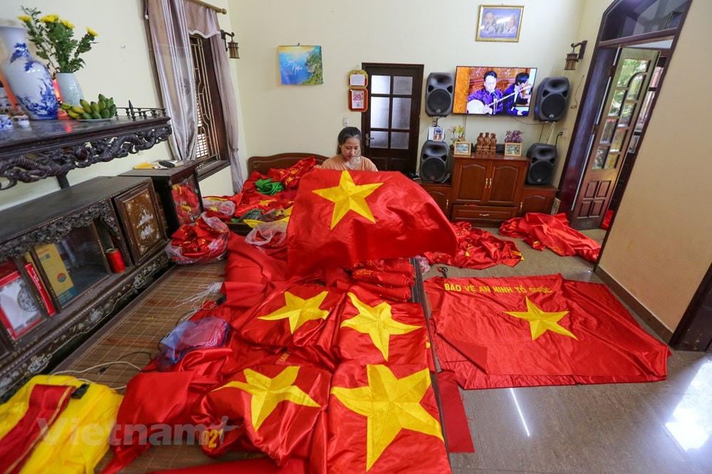 Chị Nhung tự hào khoe về cô con gái năm nay mới 23 tuổi, nhưng cũng đã có hơn 11 năm kinh nghiệm trong nghề thêu cờ. (Ảnh: Minh Sơn/Vietnam+).