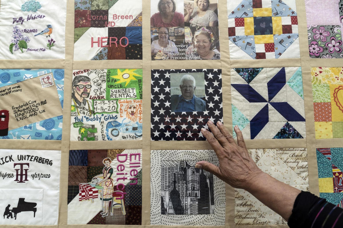 Một người đưa tay ra để chạm vào bảng điều khiển của COVID Memorial Quilt, một phần trong dự án của Madeleine Fugate nhằm tôn vinh và tưởng nhớ tất cả những người đã mất vì COVID-19, được trưng bày tại Trung tâm Khoa học California ở Los Angeles
