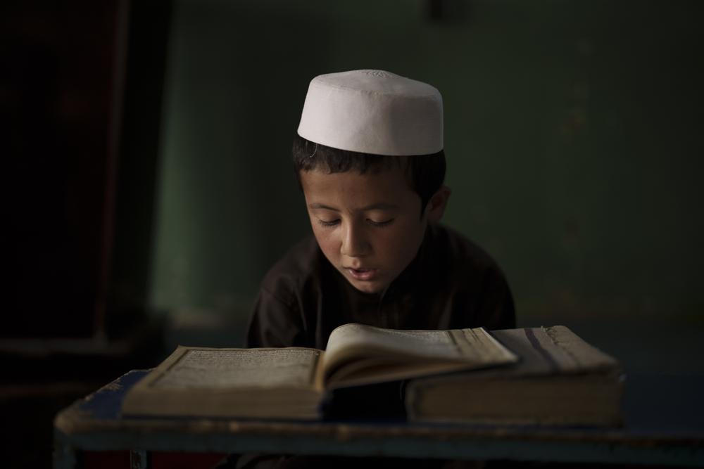Một đứa trẻ đang đọc Kinh Qur'an, cuốn sách thánh của Hồi giáo, tại một Madrasa (trường trung học Hồi giáo) ở thủ đô Kabul, Afghanistan, vào ngày 28/9/2021. Ảnh: Felipe Dana/AP.