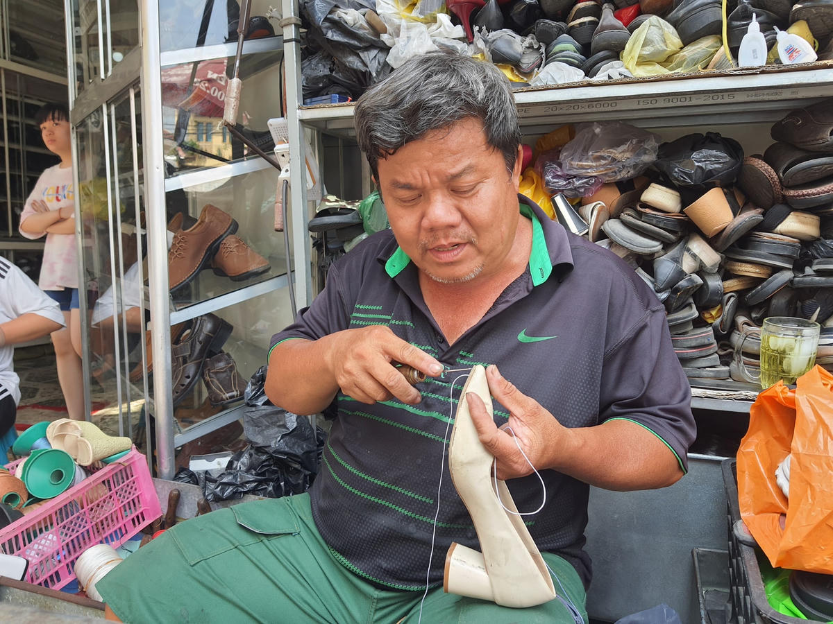 Anh Chánh tranh thủ may dép kịp giao khách. Ngày cận Tết, khách đem giày, dép đến may nhiều, công việc này giúp anh kiếm được khoảng tiền mua sắm Tết.