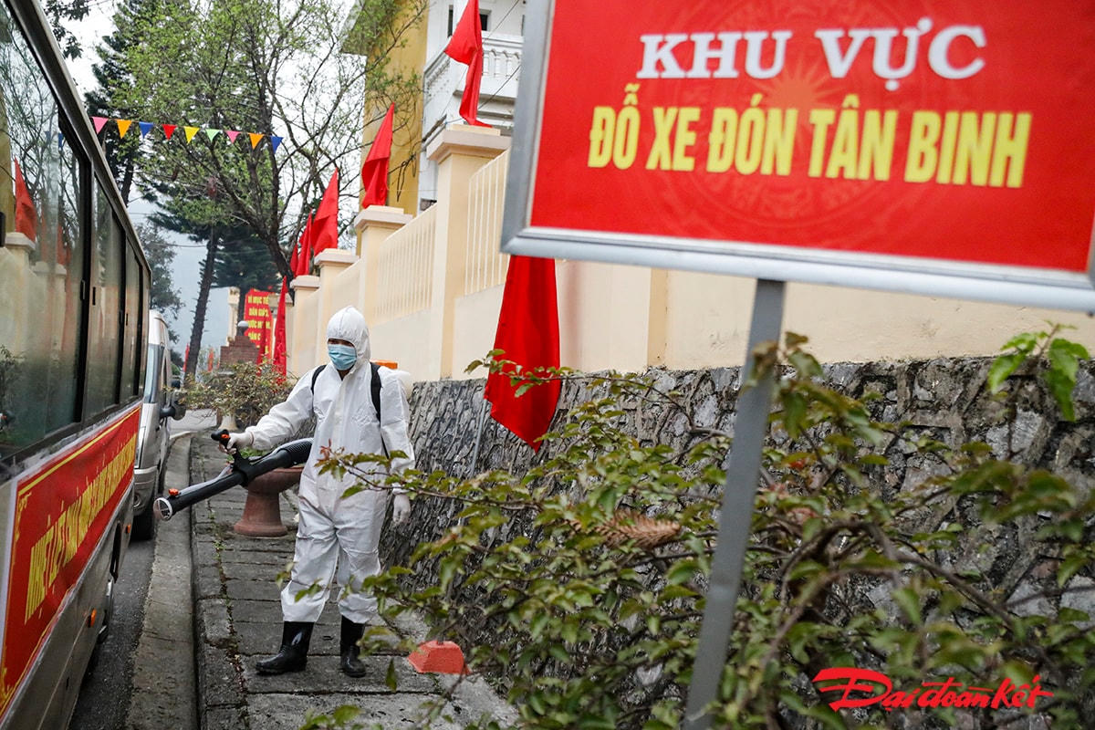 Nhân viên y tế phun khử khuẩn xe đón các tân binh trước khi vào Ban chỉ huy quân sự huyện.
