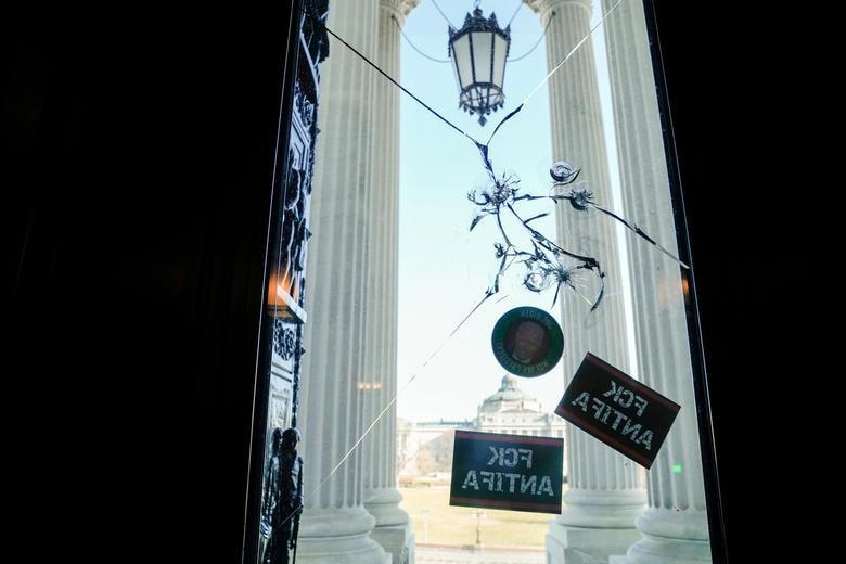 Các lỗ đạn và hình dán trên lối vào điện Capitol. Ảnh: Reuters.