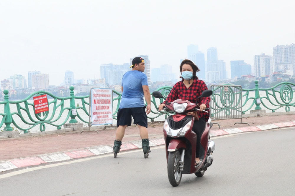 Nam thanh niên vô tư trượt patin quanh bờ hồ mà không đeo khẩu trang.