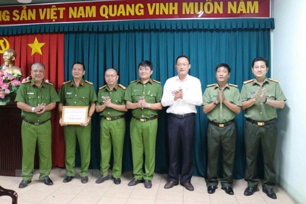 Đại tá Trần Văn Chính trao thưởng nóng 10 triệu đồng cho Công an thị xã Bến Cát. (ẢNh: TTXVN phát).