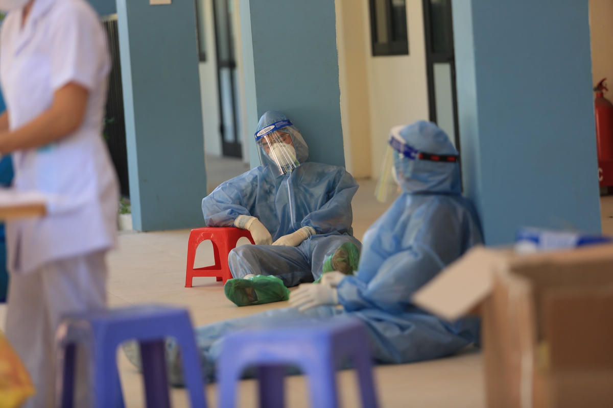 Nhiều nhân viên y tế mệt mỏi lấy những chiếc cột làm điểm tựa để nghỉ ngơi.