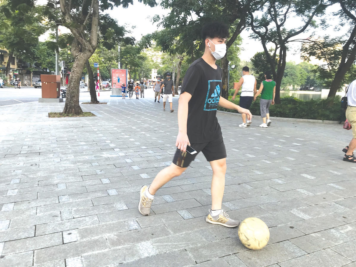 Một thiếu niên chạy rê bóng quanh bờ hồ.