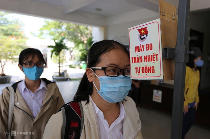 Thi sinh đưa trán áp sát vào máy sẽ cho kết quả nhiệt độ sau hai giây. Ảnh: Đắc Thành.