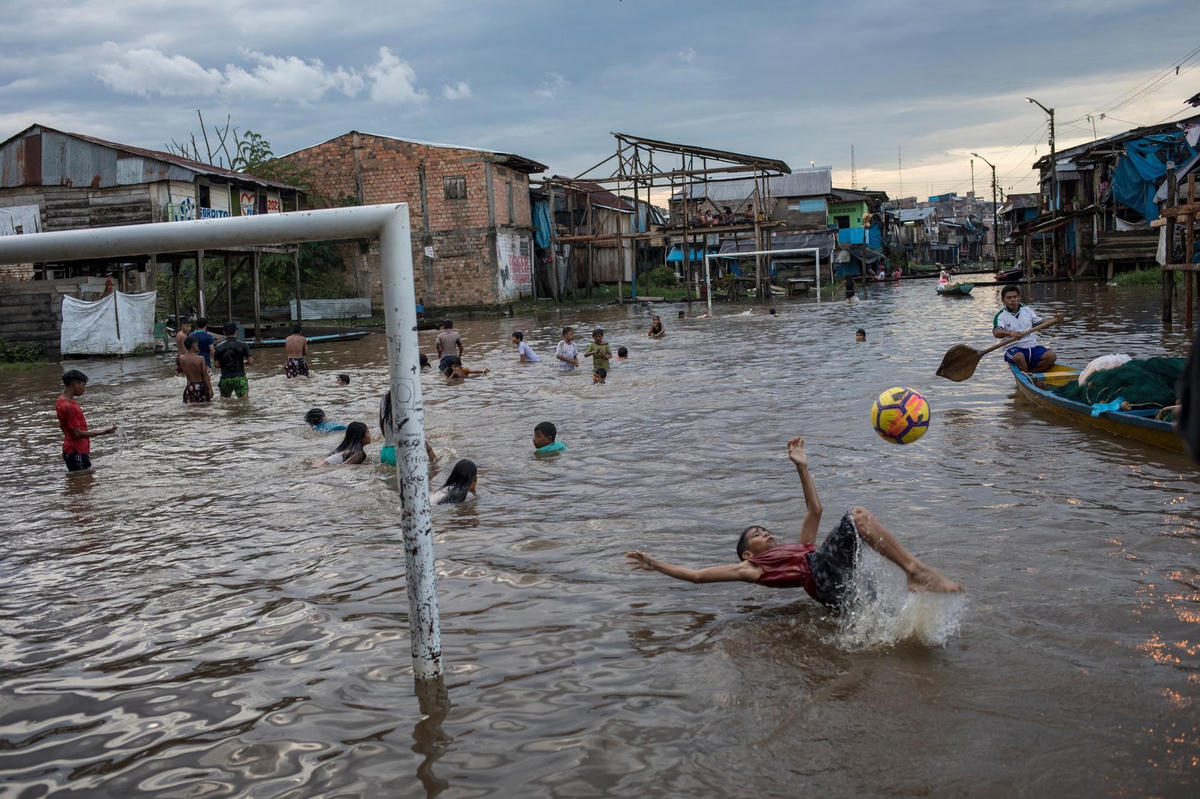 Những đứa trẻ nô đùa trong khu vực ngập lụt của cộng đồng ở Iquitos, Peru, vào ngày 20/3/2021. Ảnh: AP.  