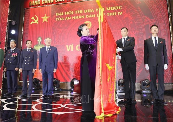 Chủ tịch Quốc hội Nguyễn Thị Kim Ngân gắn Huân chương Độc lập hạng Nhất lên lá cờ truyền thống của TAND tối cao. Ảnh. TTXVN.