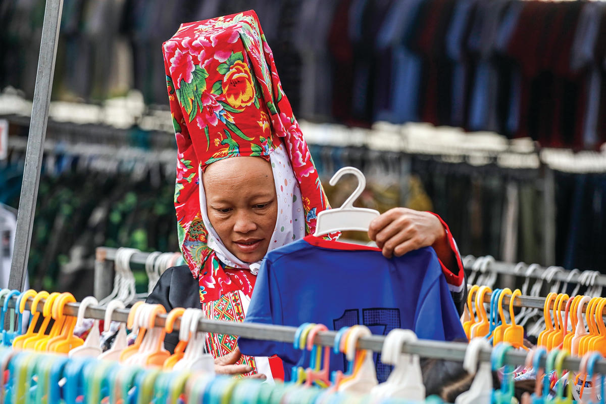 Phụ nữ Dao Thanh Phán đi chợ mua quần áo cho con.