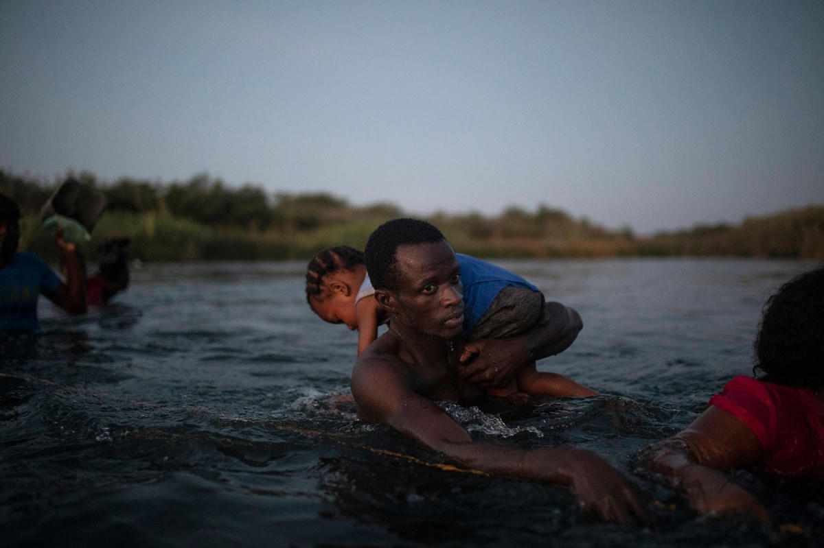 Người di cư Haiti lội qua Rio Grande từ Del Rio (Texas) đến Ciudad Acuña (Mexico) vào ngày 19/9/2021, để tránh bị Mỹ trục xuất trở về Haiti. Ảnh: AP.  