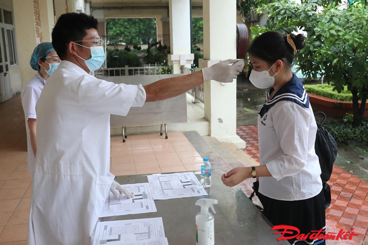 Các thí sinh phải thực hiện khai báo y tế, kiểm tra thân nhiệt và sát khuẩn tay đầy đủ trước khi vào khu vực phòng thi. Ảnh: Quang Vinh.