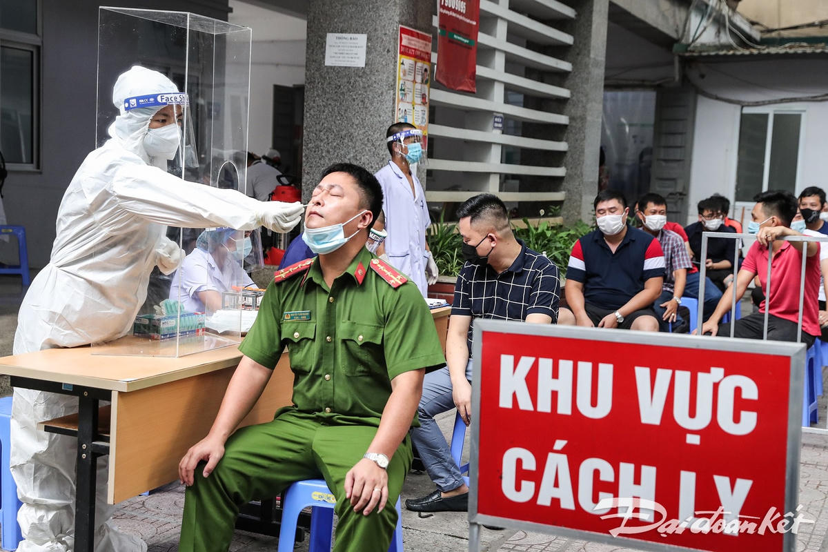Từng người lên lấy mẫu xét nghiệm, cán bộ y tế được ngăn cách bởi 1 tấm mica trắng, đảm bảo khoảng cách an toàn. Ảnh: Quang Vinh. 