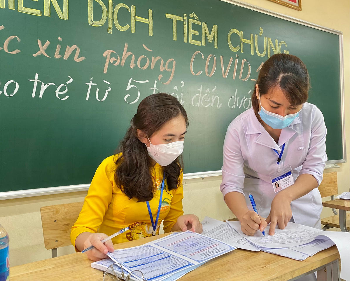 Các cô giáo cùng nhân viên y tế ghi phiếu tiêm cho các em học sinh đã hoàn thành tiêm vaccine phòng Covid-19 mũi 1.