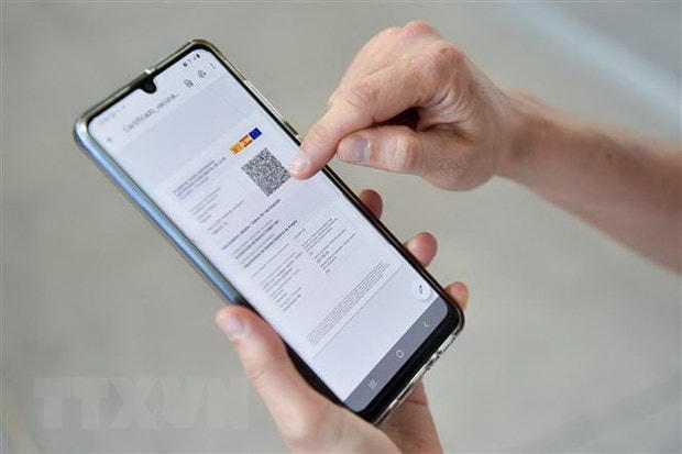 Một hành khách kiểm tra chứng nhận kỹ thuật số của Liên minh châu Âu (EU) về Covid-19 (còn gọi là hộ chiếu vaccine) được cài đặt trên điện thoại di động tại sân bay ở Barcelona, Tây Ban Nha. (Ảnh: AFP/TTXVN).