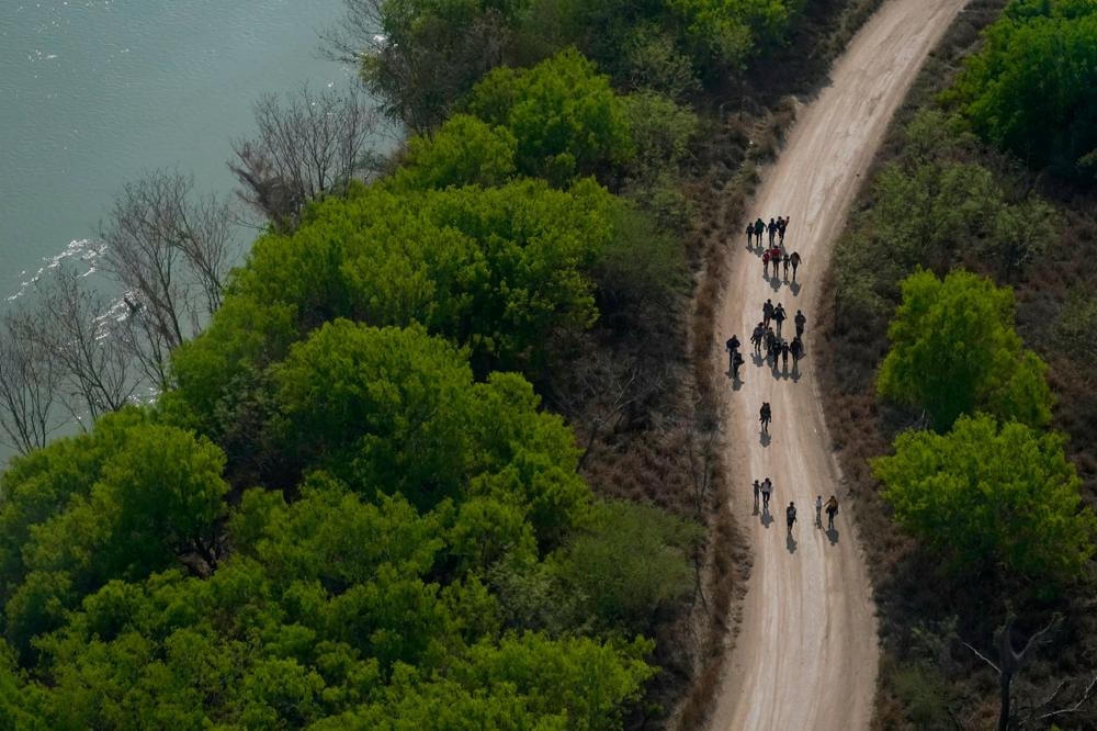 Những người di cư đi bộ trên một con đường đất dọc theo Rio Grande ở Mission, Texas vào ngày 23/3/2021, sau khi băng qua biên giới Mỹ-Mexico. Ảnh: AP.  