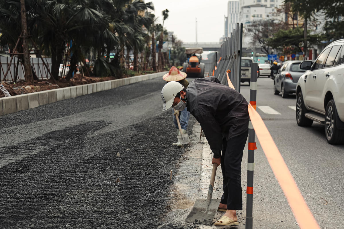 Công nhân dọn dẹp những phần sỏi đá, sau khi đầm lu bị tung ra đường đảm bảo an toàn giao thông.