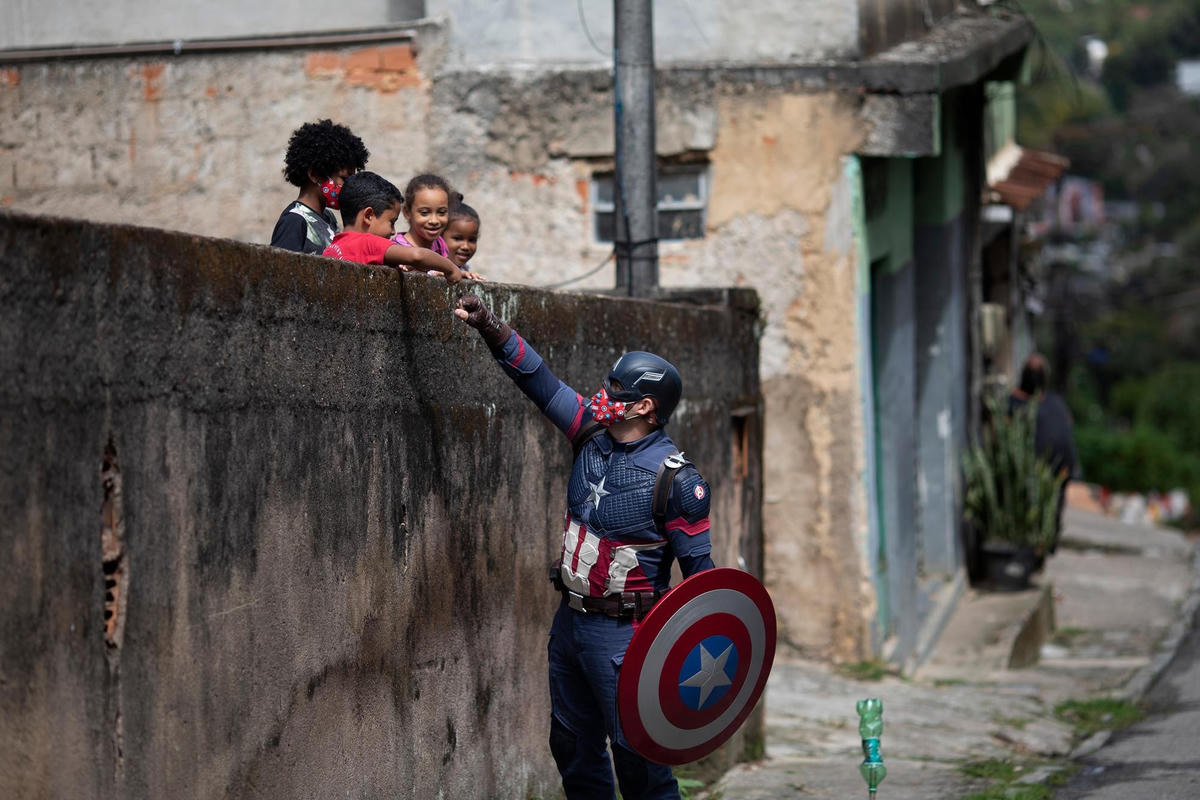 Cảnh sát quân sự Everaldo Pinto hóa trang thành siêu anh hùng Captain America, vui đùa cùng trẻ em và khuyến khích chúng tự bảo vệ bản thân trong đại dịch Covid-19 ở Petropolis, bang Rio de Janeiro, Brazil, ngày 15/4/2021. Ảnh: AP.  