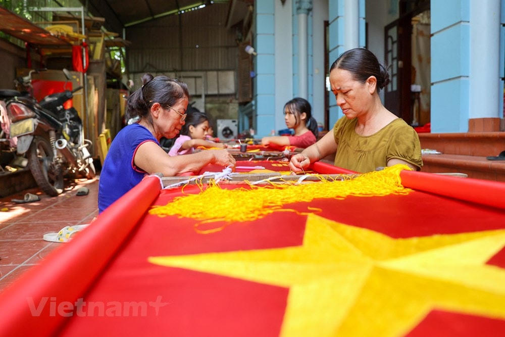 Để hoàn thiện một lá cờ thêu tay, chị Nhung phải mất 3 - 5 ngày, những người chưa thạo nghề có khi mất đến cả tuần. Những đường kim mũi chỉ phải đạt độ chuẩn xác cao vì cờ thêu được sử dụng trong các dịp lễ trang trọng. (Ảnh: Minh Sơn/Vietnam+).