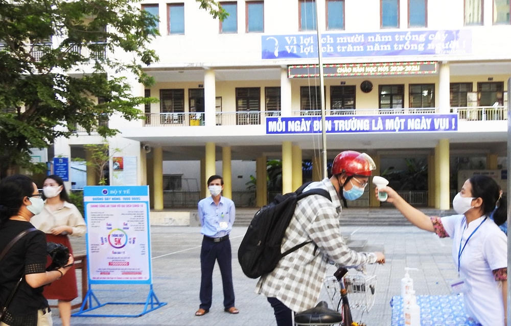Học sinh trường THPT Trần Phú (quận Hải Châu) được đo thân nhiệt, rửa tay sát khuẩn ngay khi bước qua cổng trường. Ảnh: Bình Nguyên.