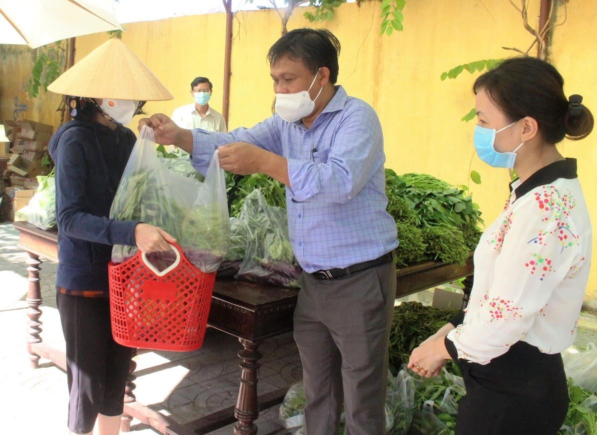 Lãnh đạo Ủy ban MTTQ Việt Nam TP Hội An (ở giữa) đưa thực phẩm cho bà con tại chợ.