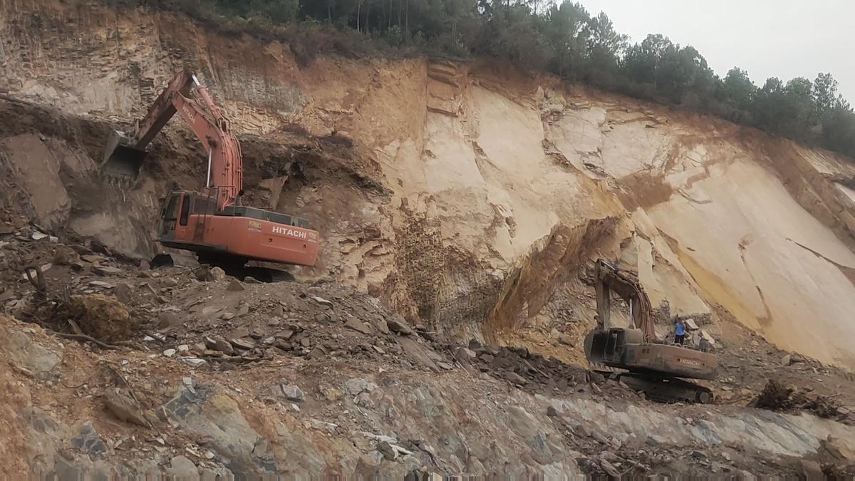 Các máy múc đào khoét nham nhở vào quả đồi.